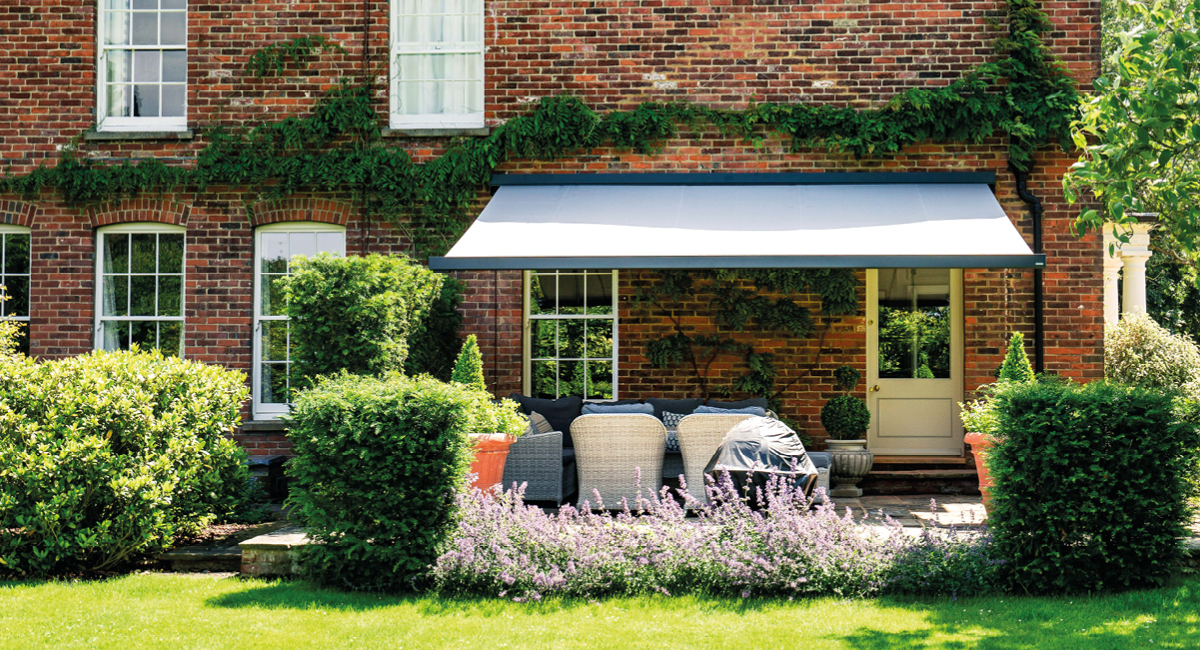 Patio awning on a country house with furniture underneath it.
