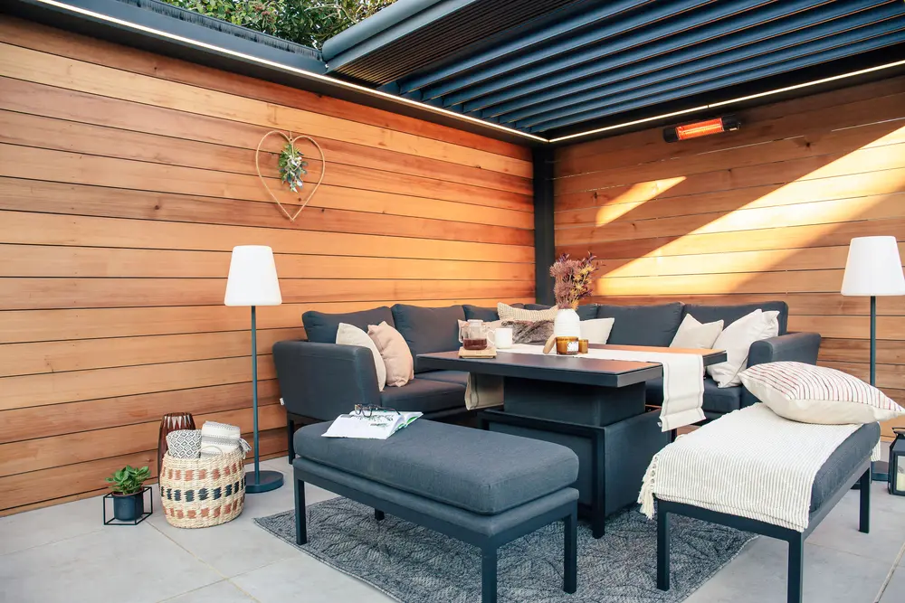 An outdoor pergola containing garden furniture.