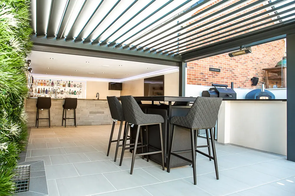A louvered pergola containing a table and chairs