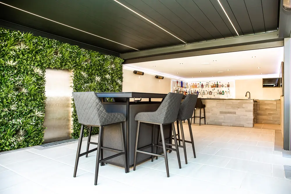 A louvered pergola containing a table and chairs
